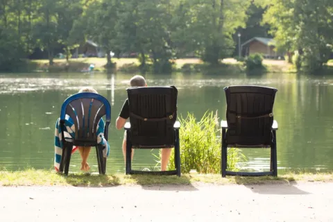 Dos personas descansan junto al lago en Domaine des Messires, un parque vacacional en Grand Est, Francia.