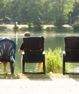 Twee personen ontspannen aan het meer bij Domaine des Messires vakantiepark in Grand Est, Frankrijk.
