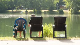 Two people relax by the lake at Domaine des Messires holiday park in Grand Est, France, enjoying nature.
