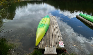 Een groene en gele kajak ligt ondersteboven op een houten steiger aan het meer in Domaine des Messires, Frankrijk.