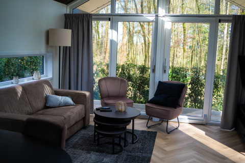 Lys stue i Bos Cottage på De Thijmse Berg, Nederlandene, med store vinduer og moderne møbler.