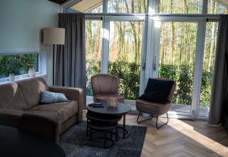 Lys stue i Bos Cottage på De Thijmse Berg, Nederlandene, med store vinduer og moderne møbler.