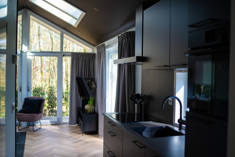 Interior moderno de la lodge Bos Cottage en De Thijmse Berg, Países Bajos, con amplios ventanales.