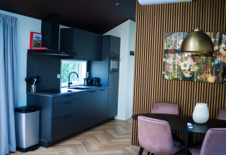 Moderne tekøkken og spiseområde i Bos Cottage ved De Thijmse Berg, Holland, med lyserøde stole.