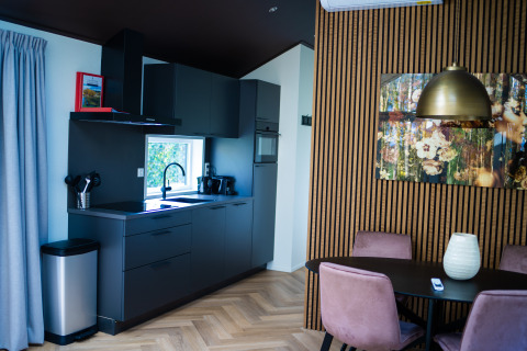 Cocina moderna y comedor en Bos Cottage, en De Thijmse Berg, Países Bajos, con sillas rosas.