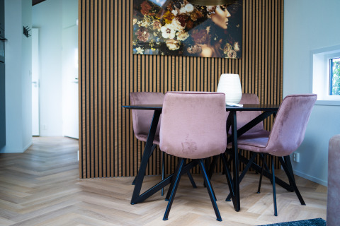 Moderne spisestue i Bos Cottage på De Thijmse Berg med lyserøde stole, sort bord og vægkunst.