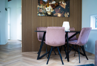 Comedor moderno en Bos Cottage en De Thijmse Berg, Países Bajos, con sillas rosas y arte de pared.