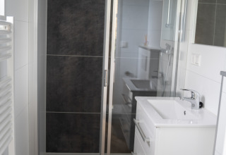 Baño moderno con ducha, lavabo y retrete en Bos Cottage, De Thijmse Berg, Países Bajos.