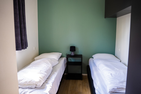 Eenvoudige slaapkamer met twee eenpersoonsbedden, nachtkastje en lamp in Heuvelrug Cottage, De Thijmse Berg.