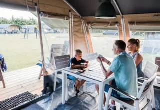 Famiglia che gioca a carte in una tenda safari, Lodge de Luxe, Domaine des Messires, Francia.