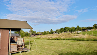 Udsigt over en safari telt hytte med privat bruser på en bondegård, omgivet af grønt landskab.