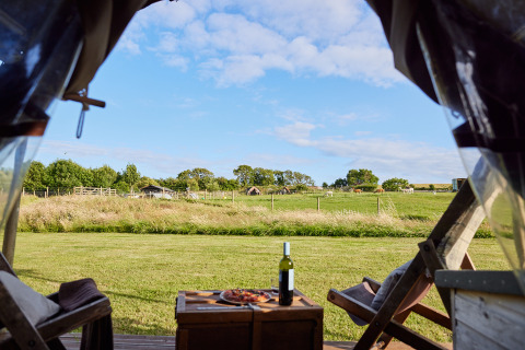 Vista desde una tienda safari con vino y pizza hacia una granja en East Shilvinghampton, Reino Unido.