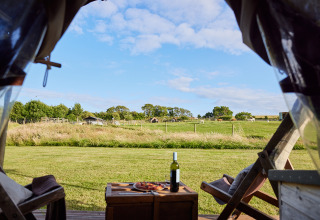 Blick aus einem Safarizelt mit Wein und Pizza auf einen Bauernhof in East Shilvinghampton, Großbritannien.