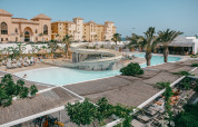 Pool area with a waterslide, palm trees, and sun loungers at Camping Costa del Sol Glamping Village, Andalusia.