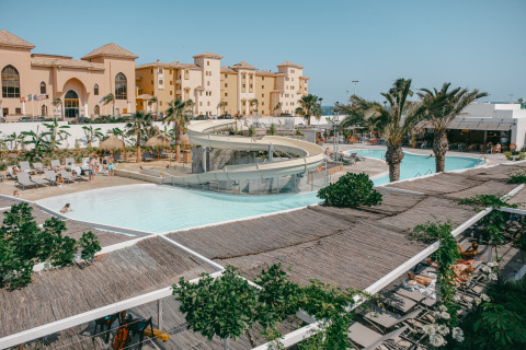 Zicht op zwembad met glijbaan, palmbomen en ligbedden bij Camping Costa del Sol Glamping Village, Andalusië.