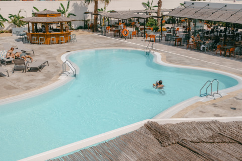 Area piscina esterna al Camping Costa del Sol Glamping Village in Andalusia, Spagna, con ospiti e bar.