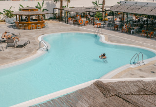 Area piscina esterna al Camping Costa del Sol Glamping Village in Andalusia, Spagna, con ospiti e bar.