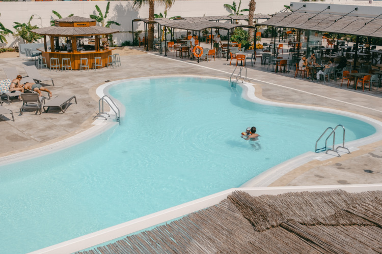 Schwimmbadbereich im Camping Costa del Sol Glamping Village mit Gästen, Bar und Sonnenliegen in Andalusien.