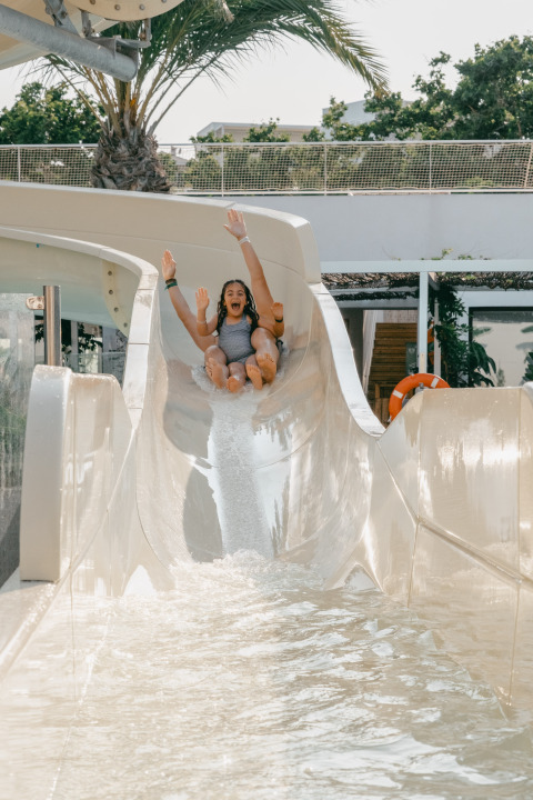 Due persone felici scendono uno scivolo d'acqua al Camping Costa del Sol Glamping Village in Andalusia, Spagna.