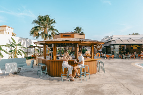 To personer nyder drinks ved en udendørs bar i Camping Costa del Sol Glamping Village i Andalusien, Spanien.