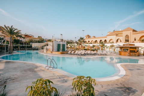 Piscina all'aperto con lettini e palme al Camping Costa del Sol Glamping Village, Andalusia, Spagna.