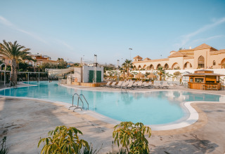 Piscina all'aperto con lettini e palme al Camping Costa del Sol Glamping Village, Andalusia, Spagna.