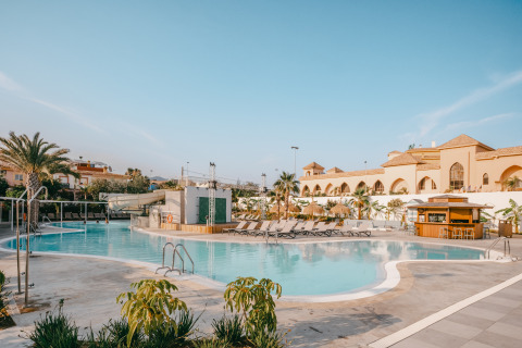 Swimming pool area at Camping Costa del Sol Glamping Village with sunbeds and bar in Andalusia, Spain.
