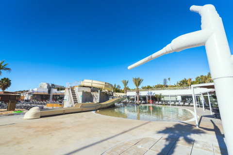Waterglijbaan en zwembad bij Camping Costa del Sol Glamping Village, Andalusië, onder een blauwe hemel.