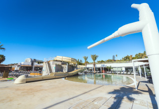 Water slide and swimming pool under clear blue sky at Camping Costa del Sol Glamping Village in Andalusia, Spain.