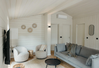 Lichte, moderne woonkamer in een Scandinavisch huisje bij Wilsumer Berge in Duitsland met comfortabele zitplaatsen.