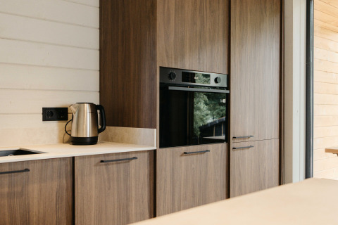Moderne cabinakeuken met houten kasten, oven en waterkoker bij Hill Top Scandi met Sauna, Wilsumer Berge, Duitsland.