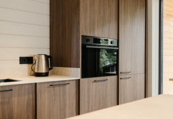 Moderne chaletkeuken met houten kasten, oven en waterkoker in Hill Top Scandi met Sauna, Wilsumer Berge, Duitsland.