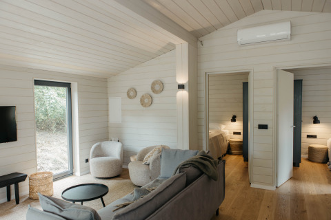 Moderne Scandinavisch cabininterieur met woonkamer, slaapkamers en ramen bij Wilsumer Berge, Duitsland.