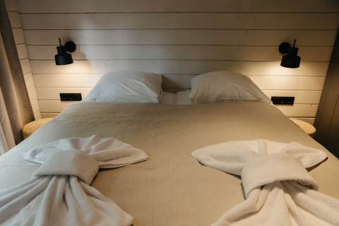 Knus bed met gevouwen handdoeken in de Hill Top Scandi met Sauna blokhut, Wilsumer Berge, Duitsland.