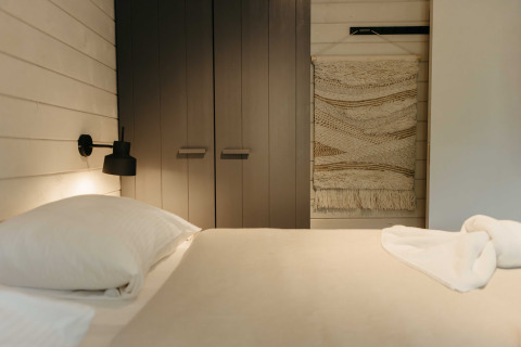Moderne slaapkamer in Hill Top Scandi met Sauna, Wilsumer Berge in Duitsland, met wandkleed en neutraal interieur.