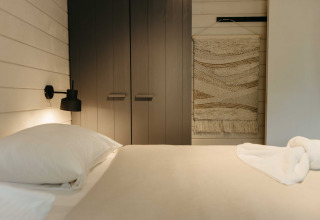 Moderne slaapkamer in Hill Top Scandi met Sauna, Wilsumer Berge in Duitsland, met wandkleed en neutraal interieur.
