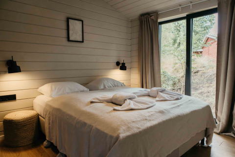 Slaapkamer in Hill Top Scandi met sauna bij Wilsumer Berge, Duitsland, met tweepersoonsbed en grote ramen.