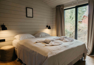 Slaapkamer in Hill Top Scandi met sauna bij Wilsumer Berge, Duitsland, met tweepersoonsbed en grote ramen.