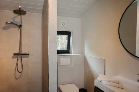 Moderne badkamer met regendouche, toilet en ronde spiegel in Hill Top Scandi met Sauna, Wilsumer Berge, Duitsland.