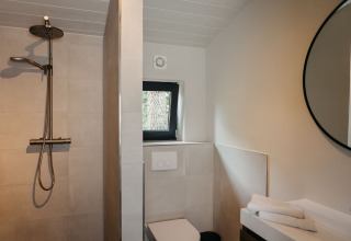 Moderne badkamer met regendouche, toilet en ronde spiegel in Hill Top Scandi met Sauna, Wilsumer Berge, Duitsland.