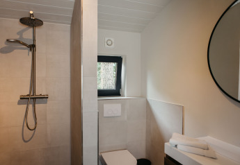 Moderne badkamer met regendouche, toilet en ronde spiegel in Hill Top Scandi met Sauna, Wilsumer Berge, Duitsland.