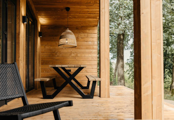 Houten terras van Hill Top Scandi met Sauna in Wilsumer Berge, Duitsland, met bank, tafel en lamp.
