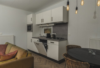 Foto degli interni della cucina del River Lodge 'Wellnesshuus' presso Holiday Park Mölke, con tavolo e divano.
