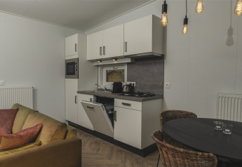 Indendørs billede af køkken i River Lodge 'Wellnesshuus' ved Holiday Park Mölke, med spisebord og sofa.