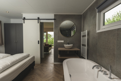 Modernes Zimmer in der River Lodge 'Wellnesshuus' mit Badewanne und Waschbecken im Holiday Park Mölke.