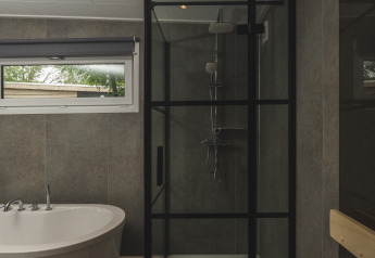 Moderne badeværelse med bruseniche og fritstående badekar i River Lodge 'Wellnesshuus' hos Mölke, Holland.