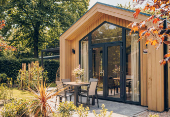 Tiny Lodge con vasca idromassaggio, esterno in legno moderno e terrazza accogliente immersa nel verde.