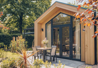 Udendørsbillede af Tiny Lodge med varmtvandskar, moderne træfacade og hyggelig terrasse i grønne omgivelser.