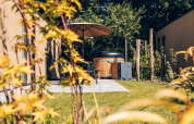 Gemütliche Terrasse mit Whirlpool, Sonnenschirm und Garten beim Tiny Lodge im Veluwepark de Bosgraaf.