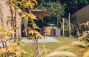 Cozy terrace with hot tub, umbrella, and garden at the Tiny Lodge in Veluwepark de Bosgraaf, Netherlands.